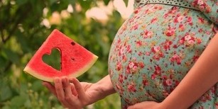 vandmelon skive i hånden på en gravid kvinde